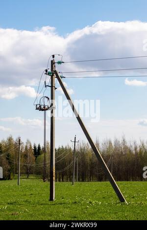 Poles with electrical wires in a green field close up Stock Photo