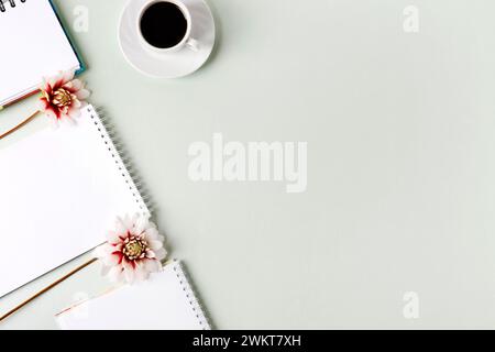 Composition with opened blank notepad, cup of black coffee, dahlia flowers on a gray background. Festive office desktop concept. Morning coffee cup. Stock Photo