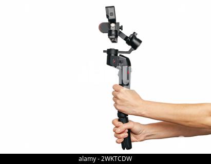 Modern black portable video and photo stabilizer in female hands on white background. Side view Stock Photo