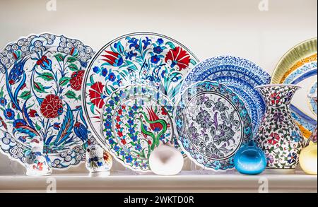 Variety of colorfully hand painted plates for sale at a market. Decorative ceramic plates on a shelf of a store. Collection of colorful ceramic potter Stock Photo