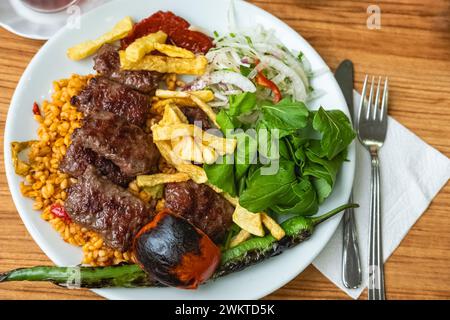 Turkish meatballs, Turkish Food Kofte or Kofta with red peppers,tomato, french fries and onion. Delicious Turkish Traditional Kebab Kofte with pilaf o Stock Photo