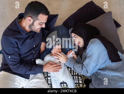 Arabic Muslim parents share a tender moment with their newborn daughter, radiating love and joy in their home. Stock Photo