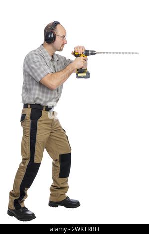 Adult male in casual attire actively using a cordless drill, isolated on a white background Stock Photo