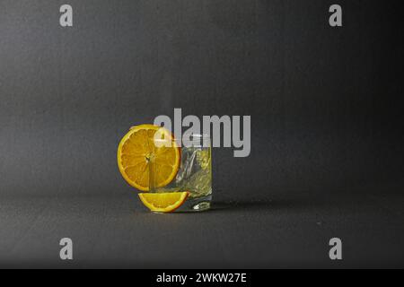glass cup with beautifully spilled juice and orange on a black background. Stock Photo