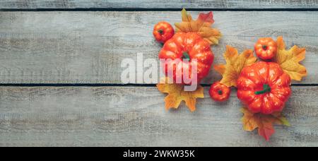 Thanksgiving and Autumn decoration concept made from autumn leaves and pumpkin on wooden light background. Flat lay, top view with copy space. Stock Photo