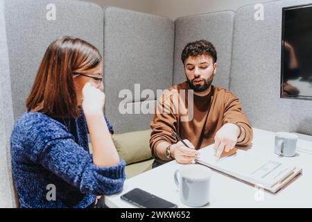 Two professionals engaged in a constructive business meeting within a contemporary office setting. Stock Photo