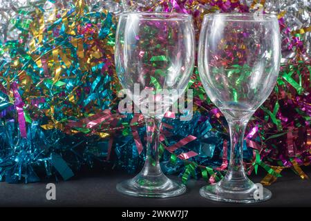 Two empty champagne glasses on a background of multicolored tinsel. Close-up. Stock Photo