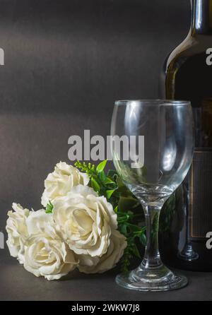 Valentine's day concept: white roses and wine bottle and empty wine glass on black background with copy space Stock Photo
