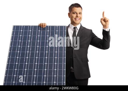 Man behind a solar panel smiling and pointing up isolated on white background Stock Photo