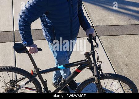 Unrecognizable man holding modern bike on the street Stock Photo