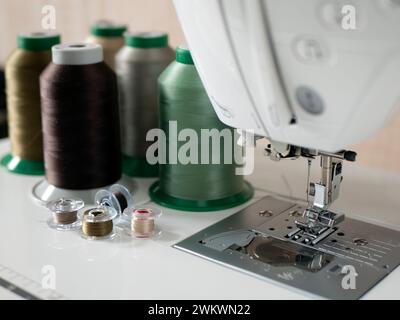 Sewing threads, bobbins and foot with needle of sewing machine, selective focus. Concept of threading the sewing machine, tailoring or making cloths Stock Photo