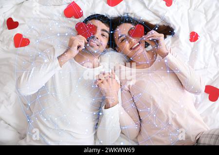 Drawn constellations and young couple with red hearts lying on bed.  Love compatibility horoscope. Partner matching by date of birth Stock Photo