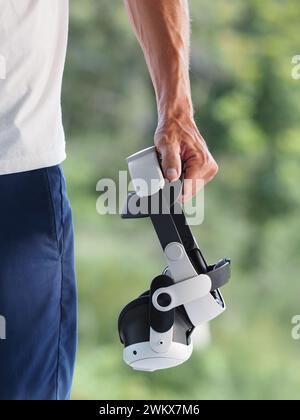 Male hand holding augmented reality goggles, VR, AR, outdoor. Close-up. Stock Photo
