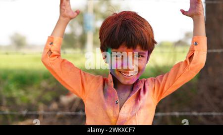 Happy Indian kids playing colours, smiling with colors on face or asian children celebrating Holi. Concept for Indian festival Holi. Bright kids smear Stock Photo