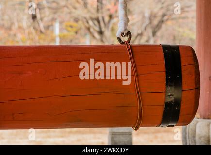 Closeup of large red wooden gong used at Buddhist temple to ring large bronze bell in South Korea Stock Photo