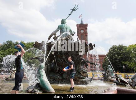 Water-hungry participants of this year's water fight at Berlin's Neptune Fountain cool off in summer temperatures on 17 June 2018. Buckets and large Stock Photo