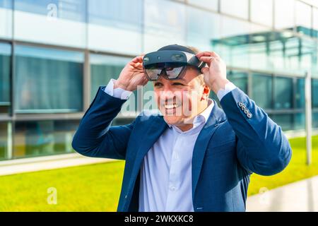 Happy businessman putting on virtual reality headset outside a financial building Stock Photo