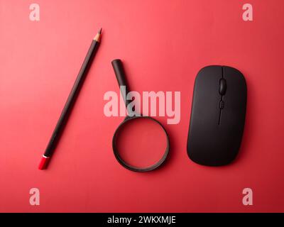 Top view wireless mouse, pencil and magnifying glass on a red background Stock Photo