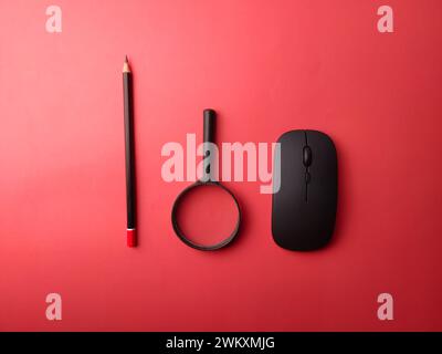 Top view arrangement wireless mouse, pencil and magnifying glass on a red background Stock Photo
