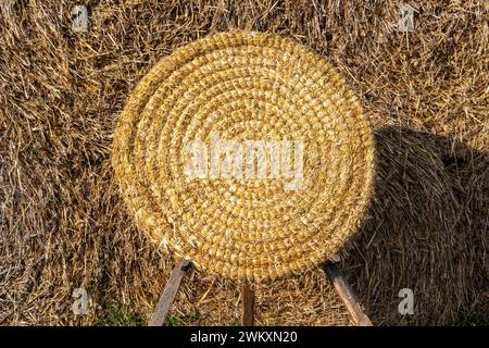 Round straw basket on hay pile with legs Stock Photo