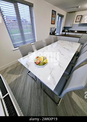 White marble table with four gray chairs and a bowl of fresh fruit on top Stock Photo