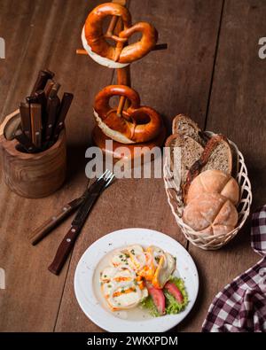 a plate of Lithuanian potato dumplings, with sour cream and chives on a wooden table Stock Photo