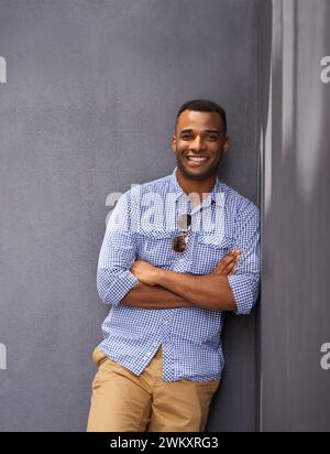 Man, smile and cool fashion in portrait by wall background, style and gen z outfit in outdoors. Happy black male person, university student and pride Stock Photo