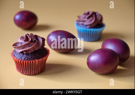Closeup of chocolate muffins and Easter eggs against yellow background Stock Photo