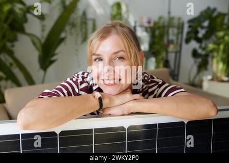 Portrait of cheerful woman leaning on solar panel she bought Stock Photo