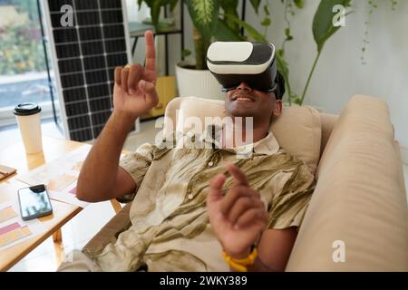 Smiling man in virtual reality headset watching video on installing solar system Stock Photo