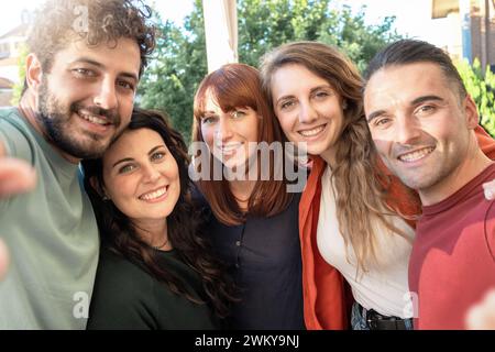 Young friends sharing a joyful moment taking a group selfie - Happiness and friendship in a casual outdoor setting Stock Photo