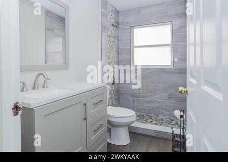 A white and gray bathroom with a sink, mirror, and cabinets Stock Photo