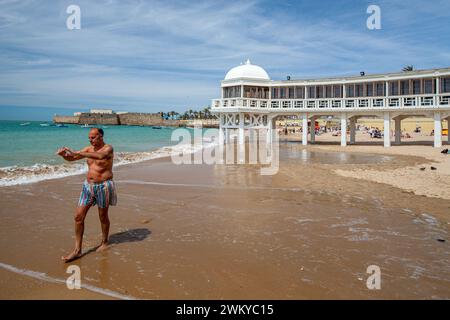 A middle-aged man is deeply focused on performing Tai Chi, a traditional Chinese martial art known for its slow movements and deep breathing, on the s Stock Photo