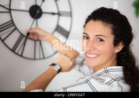 young woman changing the time on a wall clock Stock Photo