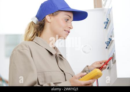 female electrician using multimeter on circuit breaker cabinet Stock Photo