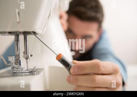 man repairing sewing machine with a screwdriver Stock Photo