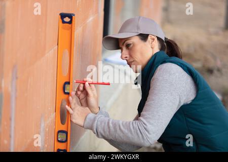 female construction worker using vertical spirit level Stock Photo
