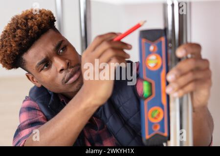 young handsome builder using spirit level equipment Stock Photo