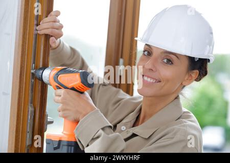 smiling female builder using cordless screwdriver Stock Photo