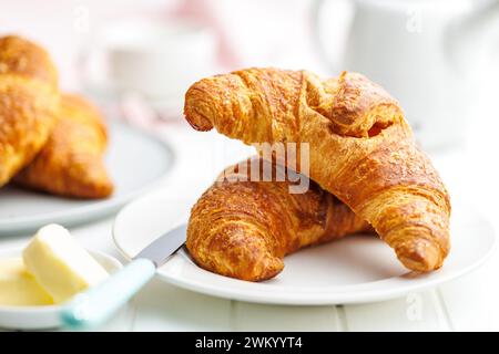 Two baked tasty croissants on plate on the white table. Stock Photo