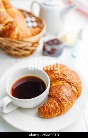 Baked tasty croissant and coffee cup on the white table. Stock Photo