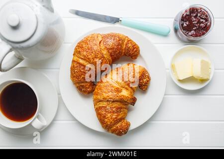 Two baked tasty croissants on plate on the white table. Top view. Stock Photo