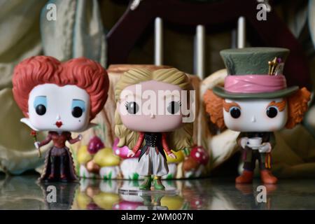 Funko Pop action figures of Mad Hatter, Red Queen and Alice in Wonderland. Palace, teapot, reflection floor, green curtain, fabulous, fantasy, moody. Stock Photo