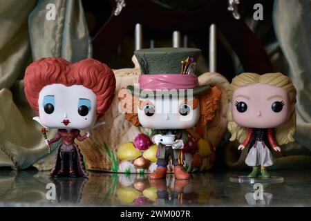 Funko Pop action figures of Red Queen, Mad Hatter and Alice in Wonderland. Palace, columns, teapot, reflection floor, green curtain, fabulous, moody. Stock Photo