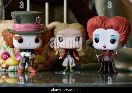 Funko Pop action figures of Mad Hatter, Red Queen and Alice in Wonderland. Palace, teapot, reflection floor, green curtain, fabulous, fantasy, moody. Stock Photo