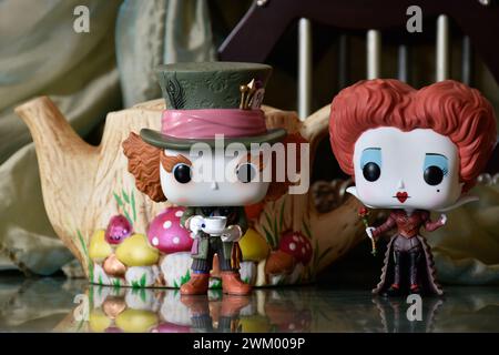 Funko Pop action figures of Mad Hatter and Red Queen, Alice in Wonderland. Handmade colorful teapot, fabulous palace, reflection floor, green curtain. Stock Photo