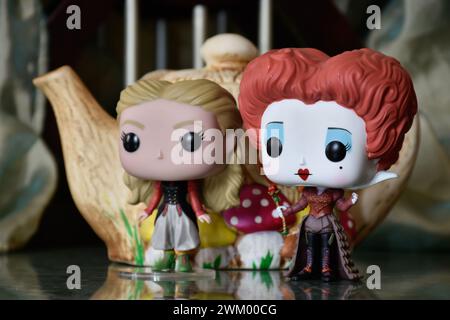 Funko Pop action figures of Red Queen and Alice in Wonderland. Colorful teapot, fabulous palace, columns, reflection floor, green curtain, fantasy. Stock Photo