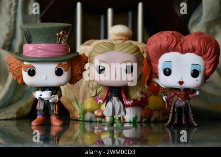 Funko Pop action figures of Mad Hatter, Red Queen and Alice in Wonderland. Palace, teapot, reflection floor, green curtain, fabulous, fantasy, moody. Stock Photo