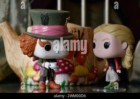Funko Pop action figures of Mad Hatter and Alice in Wonderland. Palace, columns, teapot, reflection floor, green curtain, fabulous, fantasy, moody. Stock Photo