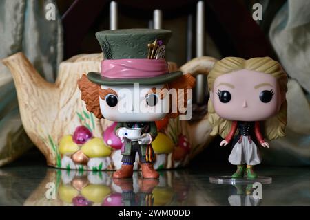 Funko Pop action figures of Mad Hatter and Alice in Wonderland. Palace, columns, teapot, reflection floor, green curtain, fabulous, fantasy, moody. Stock Photo